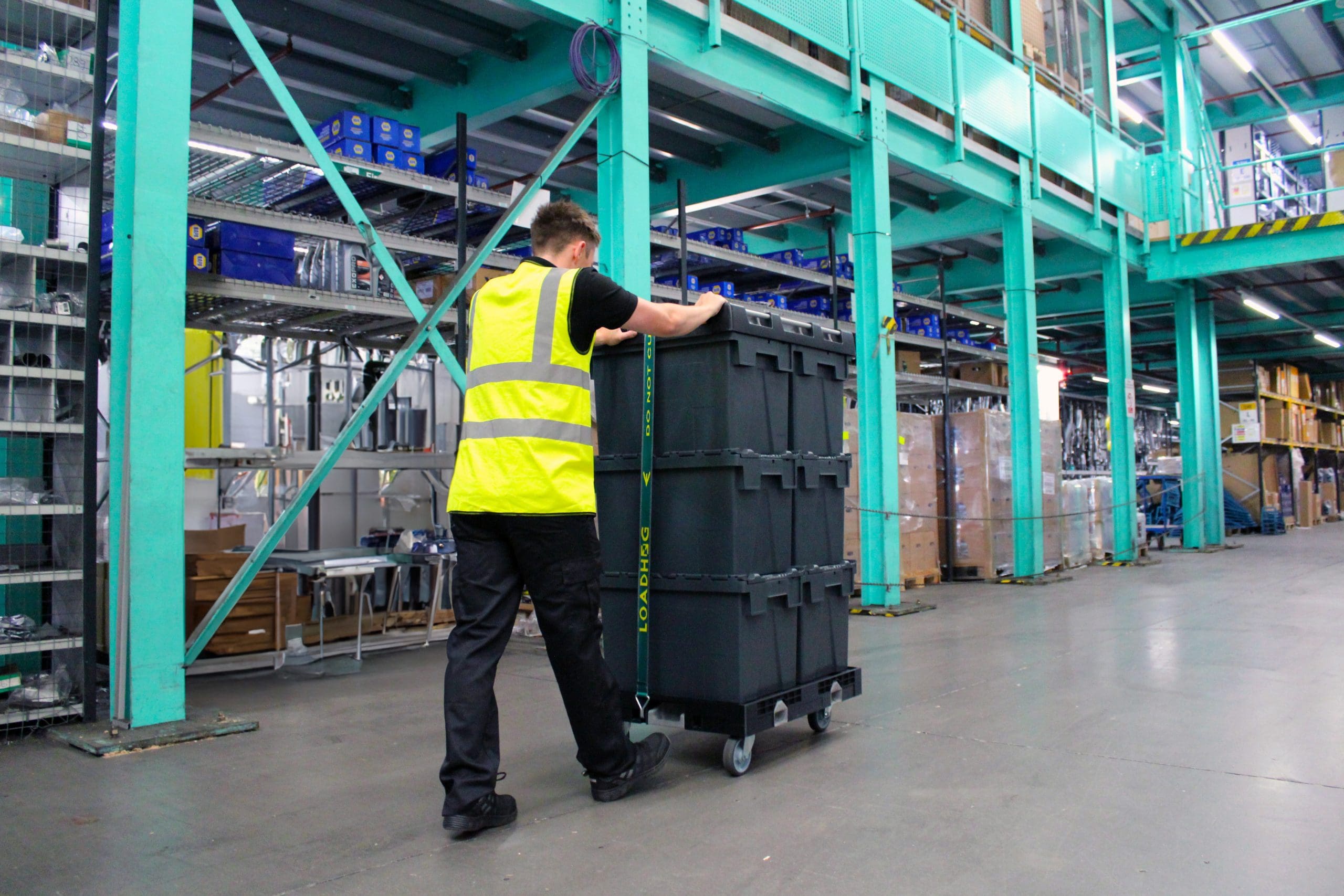 warehouse operative pushing large container system in supply chain